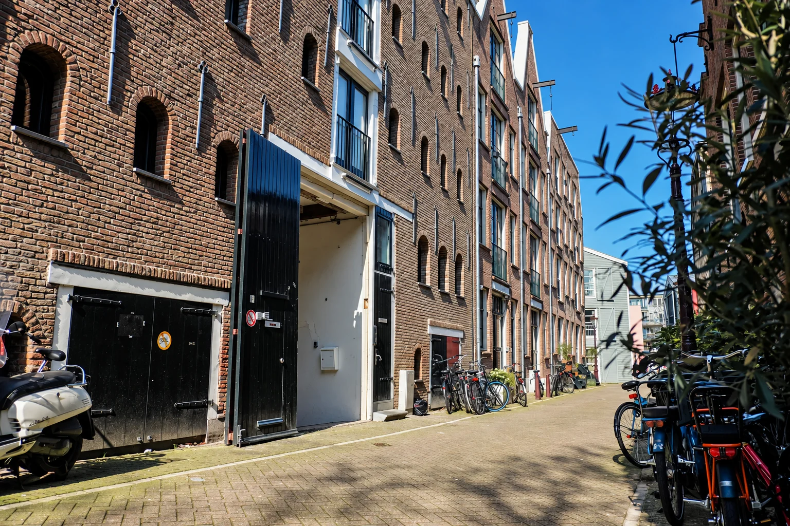Prinseneiland in Amsterdam: old brick warehouses with black wooden doors along a quiet street, bikes against the walls